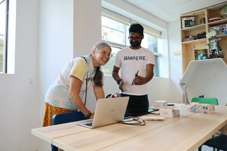 Two Ampere employees standing in the makerspace, with a computer in front of them.