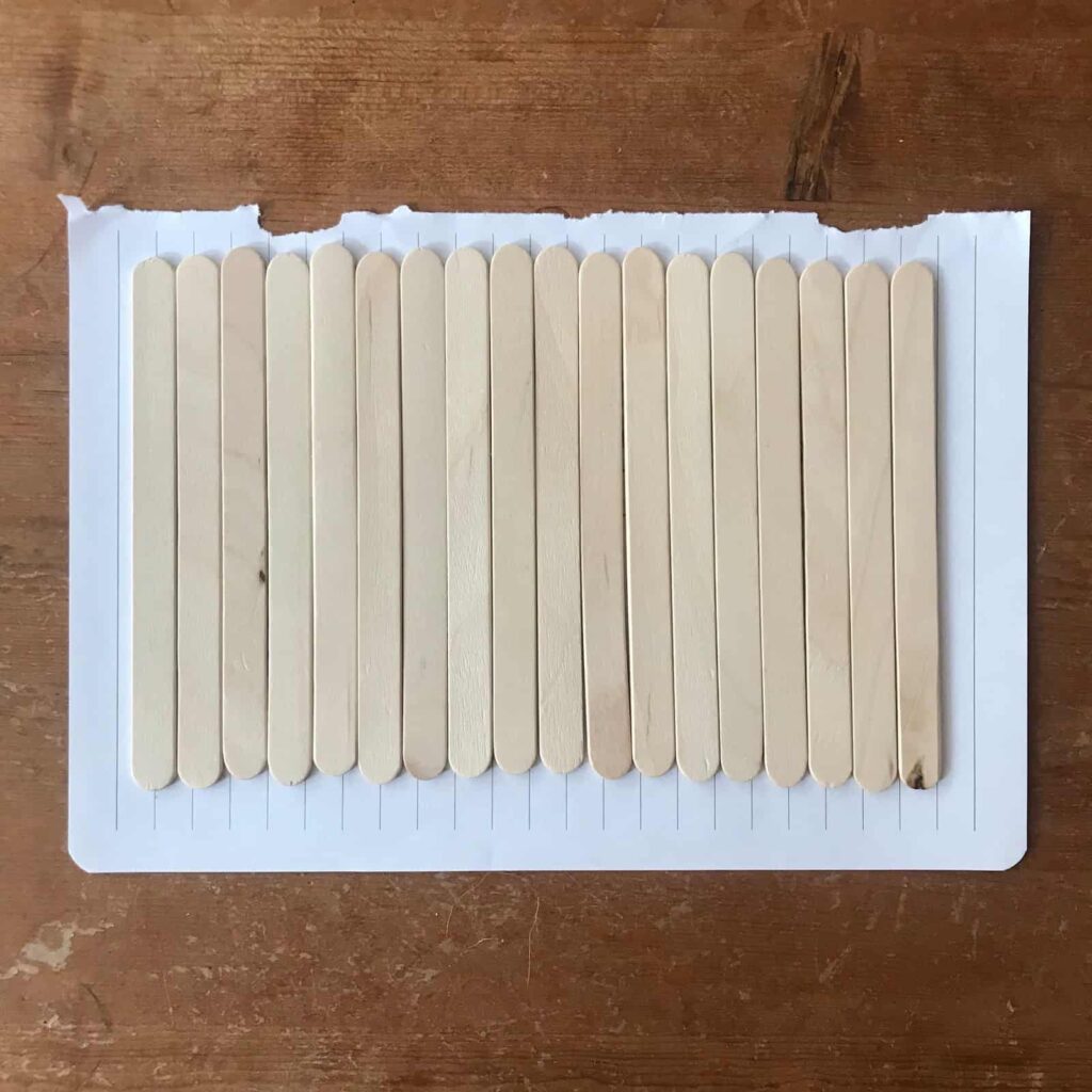 Popsicle sticks lined on a piece of paper.