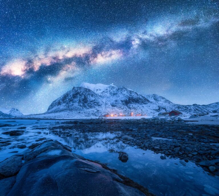 Stars shining bright over a lake and mountain.