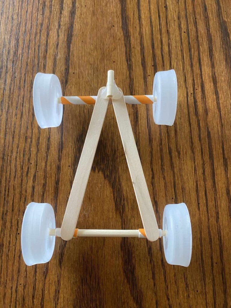 A race car made out of bottle caps, popsicle sticks, and straws.