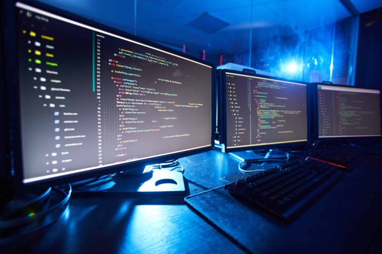Code shown on multiple computer screens.