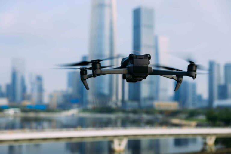 A drone flying in the air with buildings in the background.